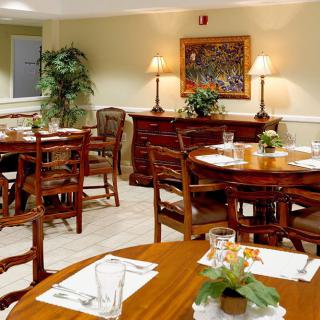 A cozy and elegantly furnished dining area with wooden tables and chairs, decorated with plants and soft lighting.