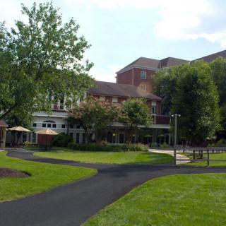A scenic view of a building surrounded by a landscaped garden with trees and a walkway.
