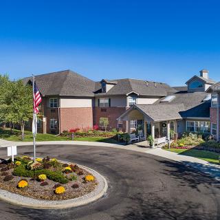 A residential building with well-maintained landscaping and an American flag on a sunny day.
