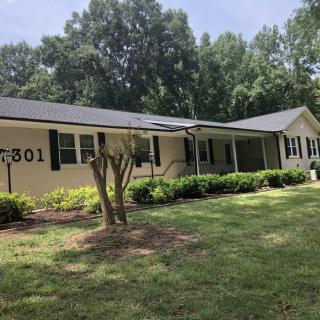 A single-story suburban house with a well-maintained front yard and surrounding trees.