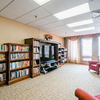 A cozy living room setup with bookshelves filled with books, a TV unit, and comfortable seating by the window.