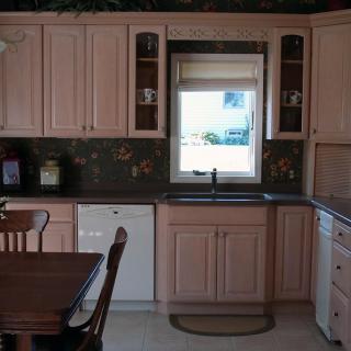 A kitchen with wooden cabinets, a window above the sink, and a dining area.