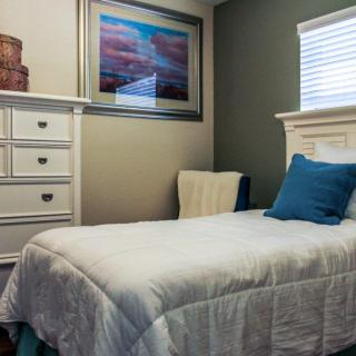 A cozy bedroom with a single bed, white bedding, and blue accents.