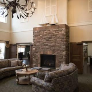 A cozy living room with a stone fireplace, elegant chandelier, and comfortable sofas.