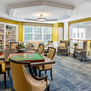 A cozy living space with a table, chairs, bookshelves, and ample natural light.