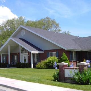 A charming residential building surrounded by lush greenery under a clear blue sky.