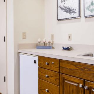 A compact kitchen area with wooden cabinets, a small refrigerator, and a sink.