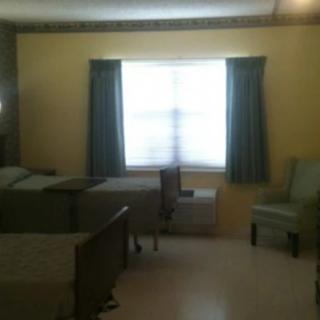 A simple room with two beds, a window with curtains, and a chair.