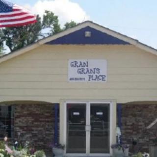A small building with a sign above the entrance and an American flag flying nearby.