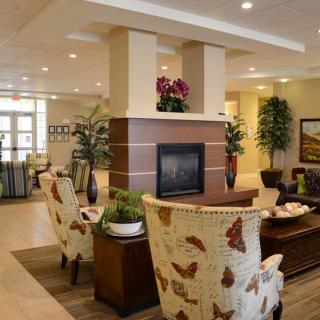 A modern lobby with comfortable seating and a central fireplace, adorned with plants and stylish decorations.