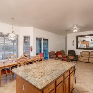 An open-concept living and dining area with a kitchen island, featuring comfortable seating and tiled flooring.