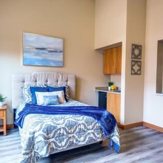 A modern bedroom with a plush bed featuring blue accents and stylish decor.