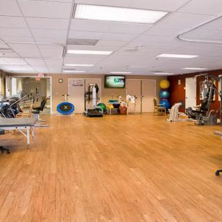 A spacious gym with various exercise equipment and a wooden floor.