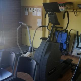 A small gym room with various fitness machines, including an elliptical and a treadmill.