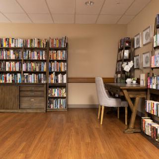 A welcoming reading nook featuring bookshelves filled with books and a comfortable table and chairs.