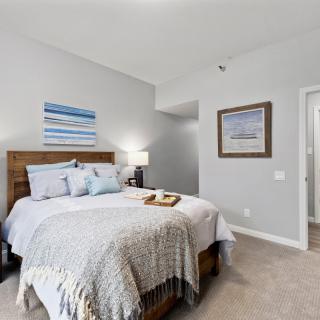 A cozy bedroom with a neatly made bed, wall art, and soft lighting.