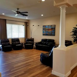 A spacious living room with leather seating, a ceiling fan, and wooden flooring.