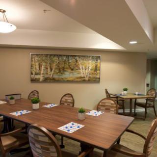 A cozy dining area with wooden tables and chairs, featuring wall art and soft lighting.