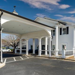 A welcoming entrance to a classic motel, featuring a charming white exterior and elegant pillars.