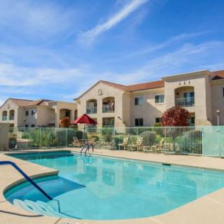 A beautiful apartment complex with a sparkling swimming pool under a clear blue sky.