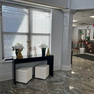 A modern lobby area with decorative vases and flowers on a sleek table beneath a large window.