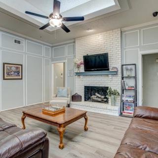 A modern living room with a fireplace, ceiling fan, and leather sofas.