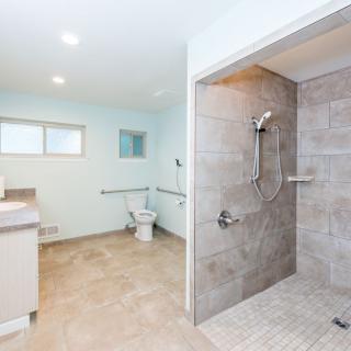 A spacious, accessible bathroom featuring a large walk-in shower and modern fixtures.