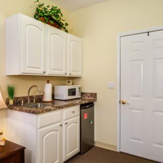 A small kitchen area with white cabinets, a microwave, and a mini fridge.