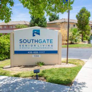 A sign for Southgate Senior Living located outside with trees and a pathway nearby.