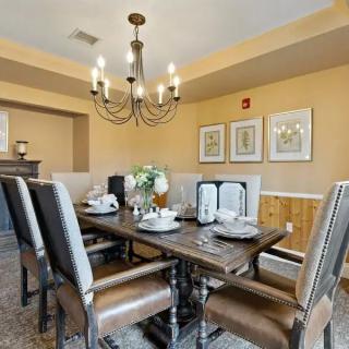 A well-decorated dining room featuring a wooden table, upholstered chairs, and an elegant chandelier.