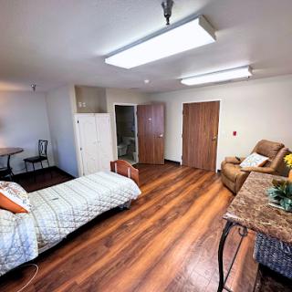A cozy and well-furnished room featuring a bed, seating area, and wooden flooring.