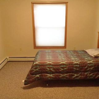 A minimalist bedroom with a bed and a window covered by a blind.