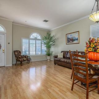 A cozy living room with a dining area, featuring hardwood floors, a sofa, chairs, and decorative elements.