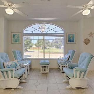 A cozy seating area with several light blue chairs arranged around a large window, illuminated by overhead ceiling fans.