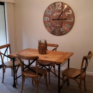 A cozy dining area featuring a wooden table and chairs, complemented by a stylish wall clock.