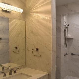 A modern bathroom featuring a marble sink, mirror, and shower area with elegant lighting.