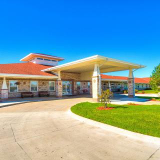 A modern building entrance with a covered walkway and landscaping on a sunny day.