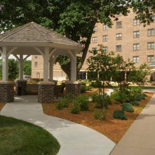 A landscaped garden with a gazebo and pathway in front of a building.