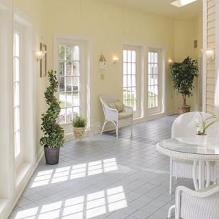 A bright sunroom with white furniture and large windows.