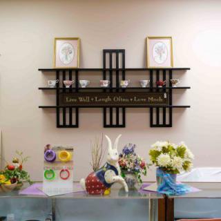 A decorative shelf on a wall adorned with flowers and various decorative items.