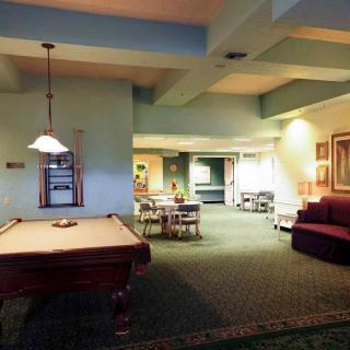 A cozy game room featuring a pool table, comfortable seating, and ambient lighting.