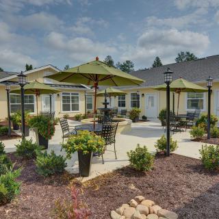 A beautifully landscaped patio area with seating and green umbrellas.