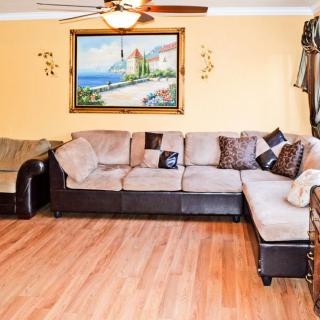 A cozy living room featuring a sectional sofa, hardwood flooring, and a scenic painting on the wall.