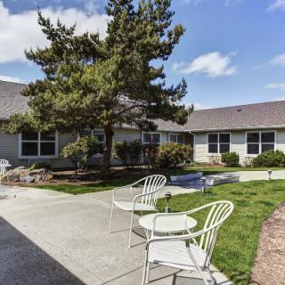 A tranquil outdoor patio area with chairs and a table surrounded by a garden and trees.