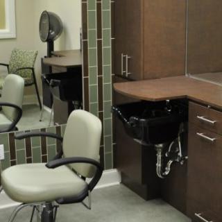 A modern hair salon interior featuring a styling chair, sink, and mirror.