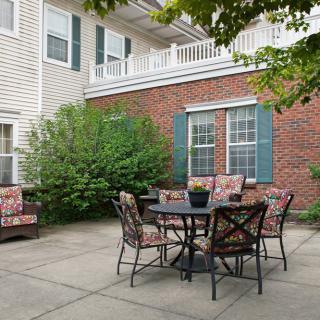 A cozy outdoor patio area with a table and chairs set against a brick wall backdrop.