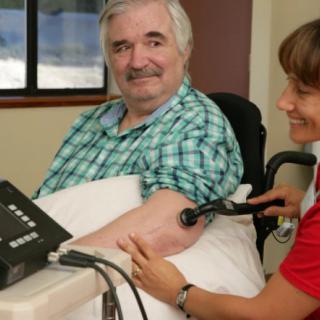 An elderly man having his blood pressure checked by a healthcare professional.