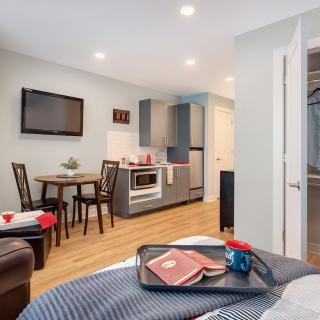 A cozy studio apartment featuring a compact kitchen and dining area with modern furnishings.