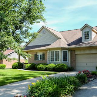 A beautiful suburban home surrounded by a well-maintained garden and trees.