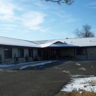 A building with a snowy roof and surrounding area, beneath a clear blue sky.
